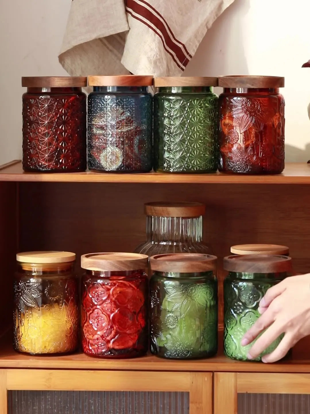 Glass storage jars with wooden lids on a kitchen shelf