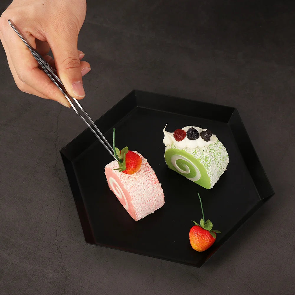 Stainless steel plating tongs placing dessert on a black plate