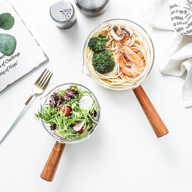Glass milk pan with wooden handle holding noodles