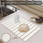 Stone dish drying mat with glasses beside a sink
