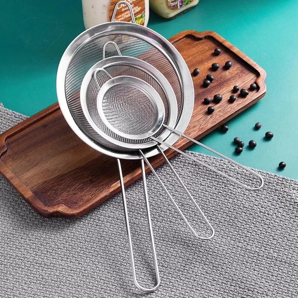 Three stainless steel fine mesh sieves on a wooden tray