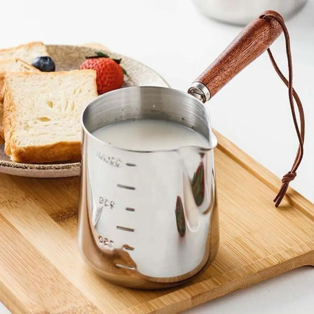 Stainless steel butter warmer with wooden handle filled with milk