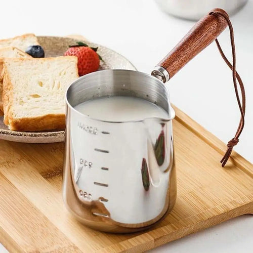 Stainless steel butter warmer with wooden handle filled with milk