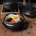 Bibimbap in a black Korean stone pot on a tray