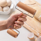 Hand holding a wooden double-ended pastry roller