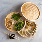 Bamboo steamer baskets with dumplings and vegetables