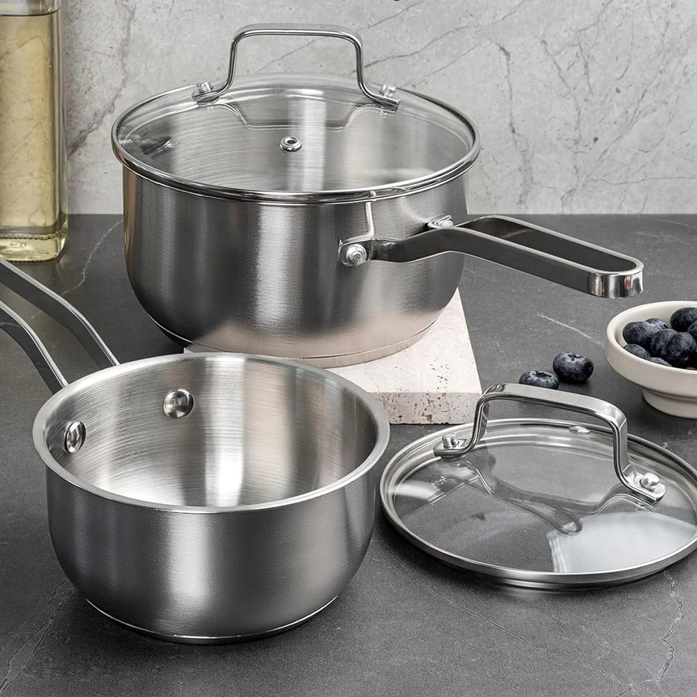 Tri-ply stainless steel saucepan with glass strainer lid on a worktop