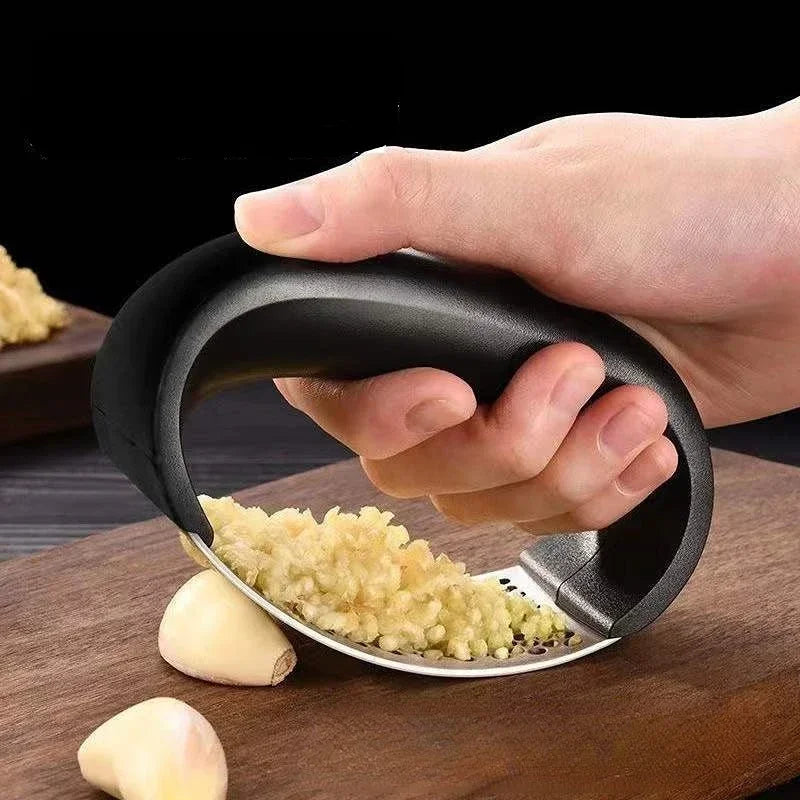 Hand pressing a garlic rocker over a clove