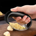 Hand pressing a garlic rocker over a clove