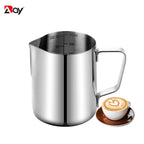 Stainless steel milk frothing jug beside a latte