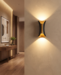 Black and gold up-down LED wall light styled in a modern hallway